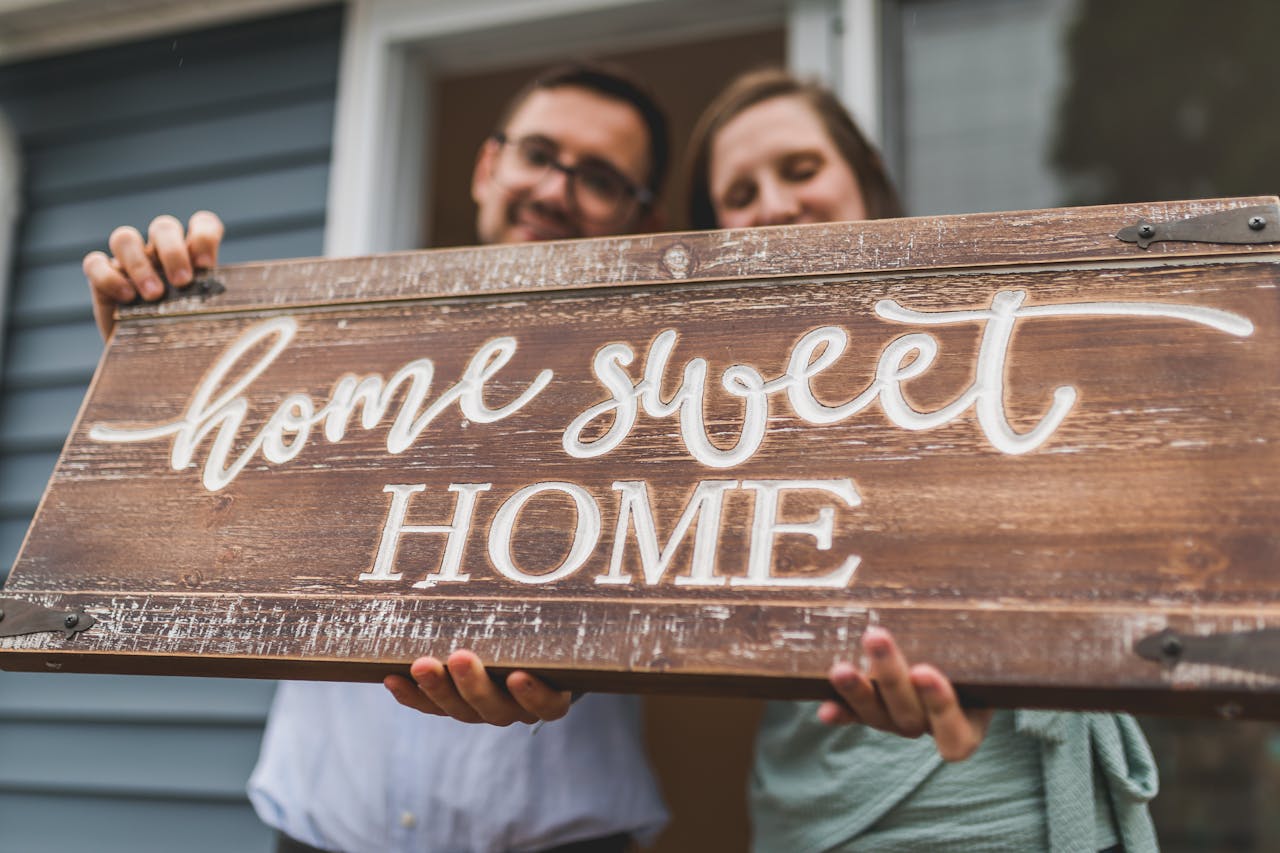 A couple holding a sign saying home sweet home